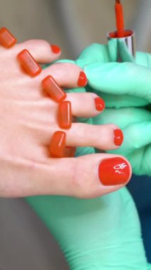 Pedikür uzmanı güzellik salonunda estetik pedikür yapıyor. Bir pedikür uzmanı genç bir kadının tırnaklarını cilalar.