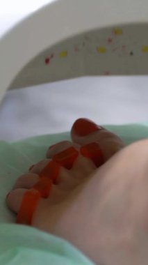 Pedikür uzmanı güzellik salonunda estetik pedikür yapıyor. Bir pedikür uzmanı genç bir kadının tırnaklarını cilalar. Oje kurutmak için UV lambası