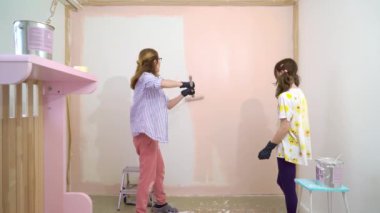 Mutlu anne ve kızın evin duvarlarını pembe renkte boyarken daire yenileme fırçasını kullanışlarının arka görüntüsü. Ev tasarımı, yenileme ve onarım konsepti.