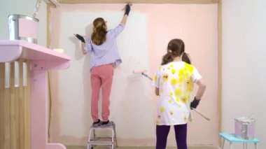 Mutlu anne ve kızın evin duvarlarını pembe renkte boyarken daire yenileme fırçasını kullanışlarının arka görüntüsü. Ev tasarımı, yenileme ve onarım konsepti.