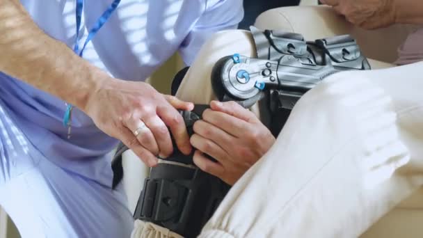 Медсестра Мужчина Помогает Установить Кабалу Медицинскую Шину Коленный Корсет Ногу — стоковое видео