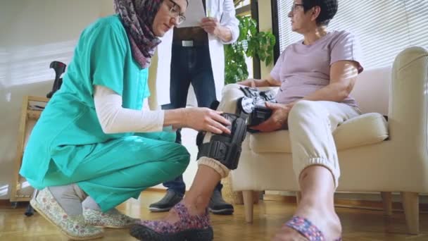 Young Muslim Nurse Wearing Hijab Helps Put Bondage Knee Brace — Stock Video