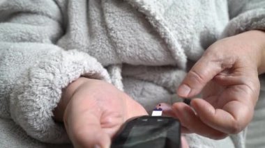 Yaşlı, şeker hastası bir kadın kan şekeri seviyesini glukometreyle ölçüyor. Sağlık hizmeti, diyabetik yaşam tarzı. Yakın plan. İzleme görüntüsü.