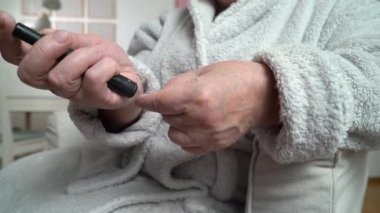 Yaşlı, şeker hastası bir kadın kan şekeri seviyesini glukometreyle ölçüyor. Sağlık hizmeti, diyabetik yaşam tarzı. Yakın plan. İzleme görüntüsü.