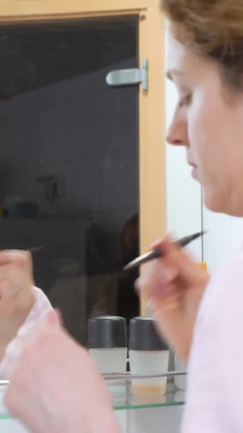 美しい慎重な中年女性は眉を描き 手でブラシを保持し バスルームにブラウジングをモデリング — ストック動画