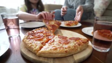 Aile pizzasını paylaşıyor. İnsan elleri sıcak İtalyan pizza pepperonisinden dilimler alıyor. İzleme görüntüsü.