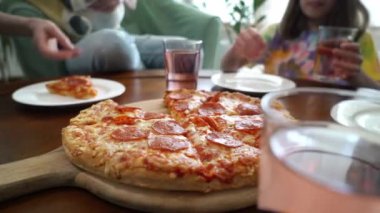 Aile pizzasını paylaşıyor. İnsan elleri sıcak İtalyan pizza pepperonisinden dilimler alıyor. İzleme görüntüsü.