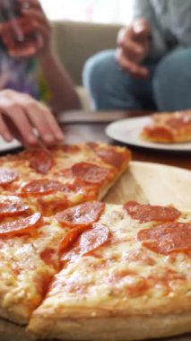 Aile pizzasını paylaşıyor. İnsan elleri sıcak İtalyan pizza pepperonisinden dilimler alıyor. İzleme görüntüsü.