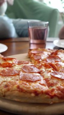 Aile pizzasını paylaşıyor. İnsan elleri sıcak İtalyan pizza pepperonisinden dilimler alıyor. İzleme görüntüsü.