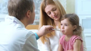 Doktor, küçük kızın sıcaklığını ölçüyor..