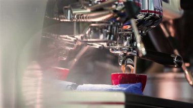 Dipsiz filtresi olan profesyonel bir kahve makinesinden Espresso kahve özütü yakın plan. Kahve fincana akıyor. Kahve aroması ve sıcak dükkan havası.