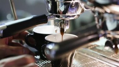 Dipsiz filtresi olan profesyonel bir kahve makinesinden Espresso kahve özütü yakın plan. Kahve fincana akıyor. Kahve aroması ve sıcak dükkan havası.