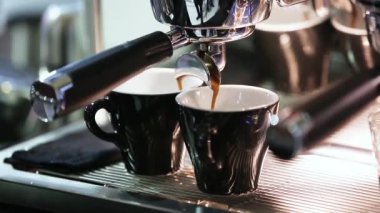 Dipsiz filtresi olan profesyonel bir kahve makinesinden Espresso kahve özütü yakın plan. Kahve fincana akıyor. Kahve aroması ve sıcak dükkan havası.