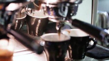 Dipsiz filtresi olan profesyonel bir kahve makinesinden Espresso kahve özütü yakın plan. Kahve fincana akıyor. Kahve aroması ve sıcak dükkan havası.