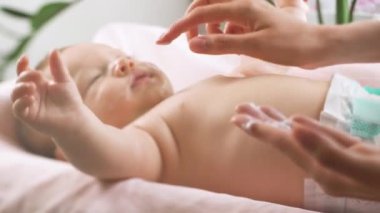 Anne kuru cilde nemlendirici krem sürüyor. Hijyen, bebek bakımı ve sağlık hizmetleri kavramı.