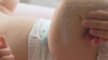 Anne kuru cilde nemlendirici krem sürüyor. Hijyen, bebek bakımı ve sağlık hizmetleri kavramı.