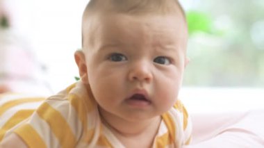 Yeni doğmuş küçük bebek yatakta uzanıyor ve gülümsüyor..