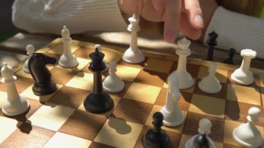 Evinin bahçesinde veya yaz parkında satranç oynayan genç bir kadın.
