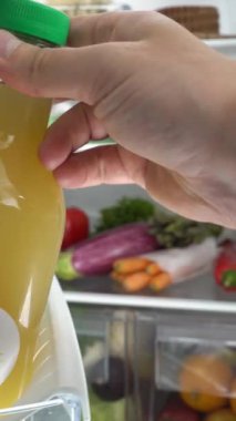 Genç bir kadın farklı yiyeceklerle dolu buzdolabının kapısını açıyor. Akıllı telefon ekranı, hedef sosyal medya platformları ve mobil aygıtlar üzerindeki web tarayıcıları için dikey video.