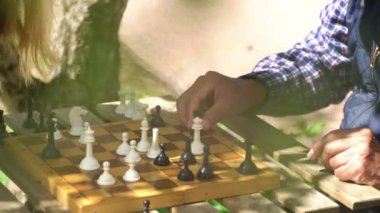 Yaşlı adam ve genç kadın bahçede satranç oynuyorlar. Boş zaman aktivitesi, akıl sağlığı ve yaşlılık, spor, eğlence, eski nesil, mutlu emekli insanlar, sağlık ve
