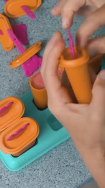 Ev yapımı buzlu şeker, dondurmalı lolipop, dondurulmuş meyve suyu. Kadınların elleri dondurma kalıbını tutar..