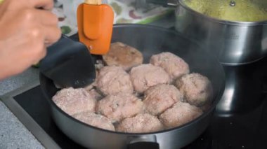 Kadın köfte pişiriyor ya da et köftesi pirzolası fırında tavada yağla kızartılıyor. Ev yemekleri, geleneksel tarifler ve aşçılık.