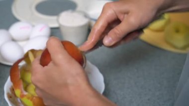 Mutfakta elmalı pasta için elma soyan ve kesen kadın.