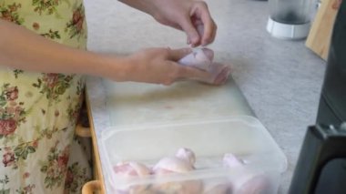 Bir kadın ev mutfağında tavuk bacağı pişiriyor. Evde yemek hazırlıyorum..