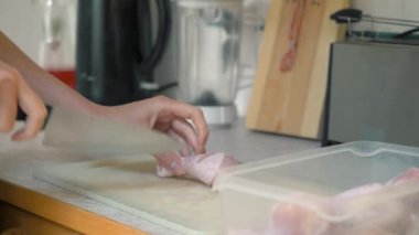 Bir kadın ev mutfağında tavuk bacağı pişiriyor. Evde yemek hazırlıyorum..