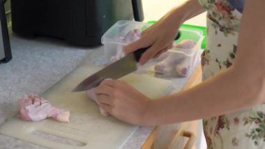 Ev hanımı mutfakta keskin bir bıçakla çiğ tavuk eti kesiyor. Bir kadın mutfakta tavuk bacağı pişirir. Evde yemek hazırlıyorum..