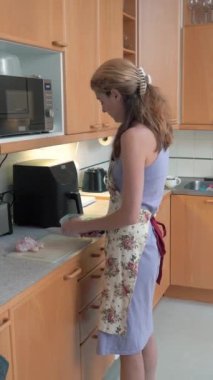 Ev hanımı mutfakta keskin bir bıçakla çiğ tavuk eti kesiyor. Bir kadın mutfakta tavuk bacağı pişirir. Evde yemek hazırlıyorum..