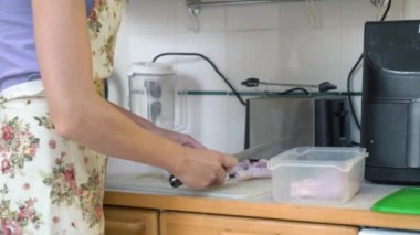 Ev hanımı mutfakta keskin bir bıçakla çiğ tavuk eti kesiyor. Bir kadın mutfakta tavuk bacağı pişirir. Evde yemek hazırlıyorum..