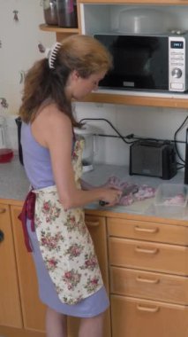 Ev hanımı mutfakta keskin bir bıçakla çiğ tavuk eti kesiyor. Bir kadın mutfakta tavuk bacağı pişirir. Evde yemek hazırlıyorum..