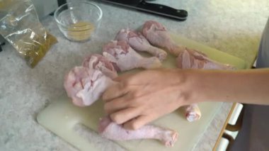 Ev hanımı mutfaktaki kesme tahtasındaki çiğ tavuğu tuzlayıp çeşnilendiriyor. Evde yemek hazırlıyorum..