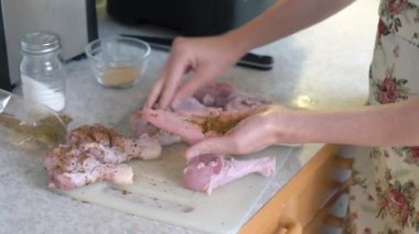 Ev hanımı mutfaktaki kesme tahtasındaki çiğ tavuğu tuzlayıp çeşnilendiriyor. Evde yemek hazırlıyorum..