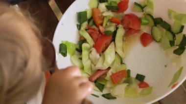 Küçük çocuk açık havada oturmuş taze sebze salatası yiyor. Çocuk sağlıklı besin konsepti