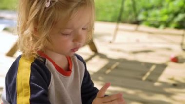 Küçük çocuk bahçedeki terasta taze meyvenin tadını çıkarıyor, canlı yeşilliklerle çevrili..