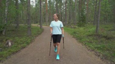Aktif kadın Finlandiya 'da ulusal bir parkta yürüyüş yapıyor, parkta spor yapıyor, egzersiz yaparak formda kalıyor.