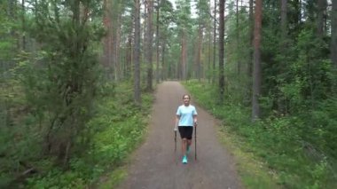 Aktif kadın Finlandiya 'da ulusal bir parkta yürüyüş yapıyor, parkta spor yapıyor, egzersiz yaparak formda kalıyor.