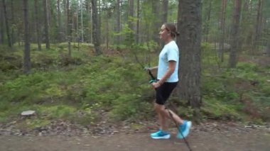 Aktif kadın Finlandiya 'da ulusal bir parkta yürüyüş yapıyor, parkta spor yapıyor, egzersiz yaparak formda kalıyor.