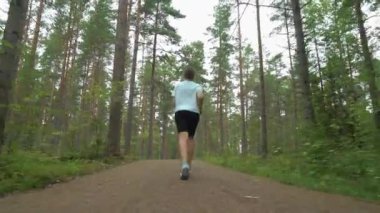 Finlandiya 'da ulusal bir parkta koşan atletik genç kadın, parkta spor yapıyor, egzersiz yaparak formda kalıyor.