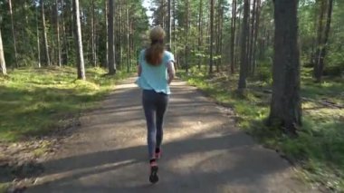 Finlandiya 'da ulusal bir parkta koşan atletik genç kadın, parkta spor yapıyor, egzersiz yaparak formda kalıyor.