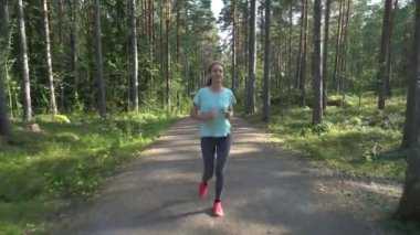 Finlandiya 'da ulusal bir parkta koşan atletik genç kadın, parkta spor yapıyor, egzersiz yaparak formda kalıyor.