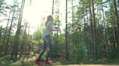 Finlandiya 'da ulusal bir parkta koşan atletik genç kadın, parkta spor yapıyor, egzersiz yaparak formda kalıyor.