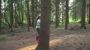 Finlandiya 'da ulusal bir parkta koşan atletik genç kadın, ormanda spor yapıyor, egzersiz yaparak formda kalıyor.