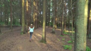 Finlandiya 'da ulusal bir parkta koşan atletik genç kadın, ormanda spor yapıyor, egzersiz yaparak formda kalıyor.