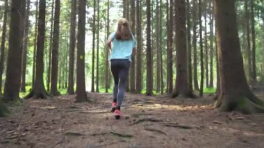 Finlandiya 'da ulusal bir parkta koşan atletik genç kadın, ormanda spor yapıyor, egzersiz yaparak formda kalıyor.