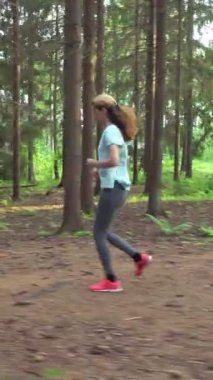 Finlandiya 'da ulusal bir parkta koşan atletik genç kadın, ormanda spor yapıyor, egzersiz yaparak formda kalıyor.