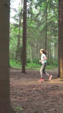 Finlandiya 'da ulusal bir parkta koşan atletik genç kadın, ormanda spor yapıyor, egzersiz yaparak formda kalıyor.