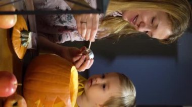 Anne, bebek ve kızı Cadılar Bayramı 'nda evde balkabağı kabağı yapıyorlar. Evde eğlenceli zanaat ve dekorasyon. Mutlu çocuklar ve anneleri tatil için hazırlanıyor.